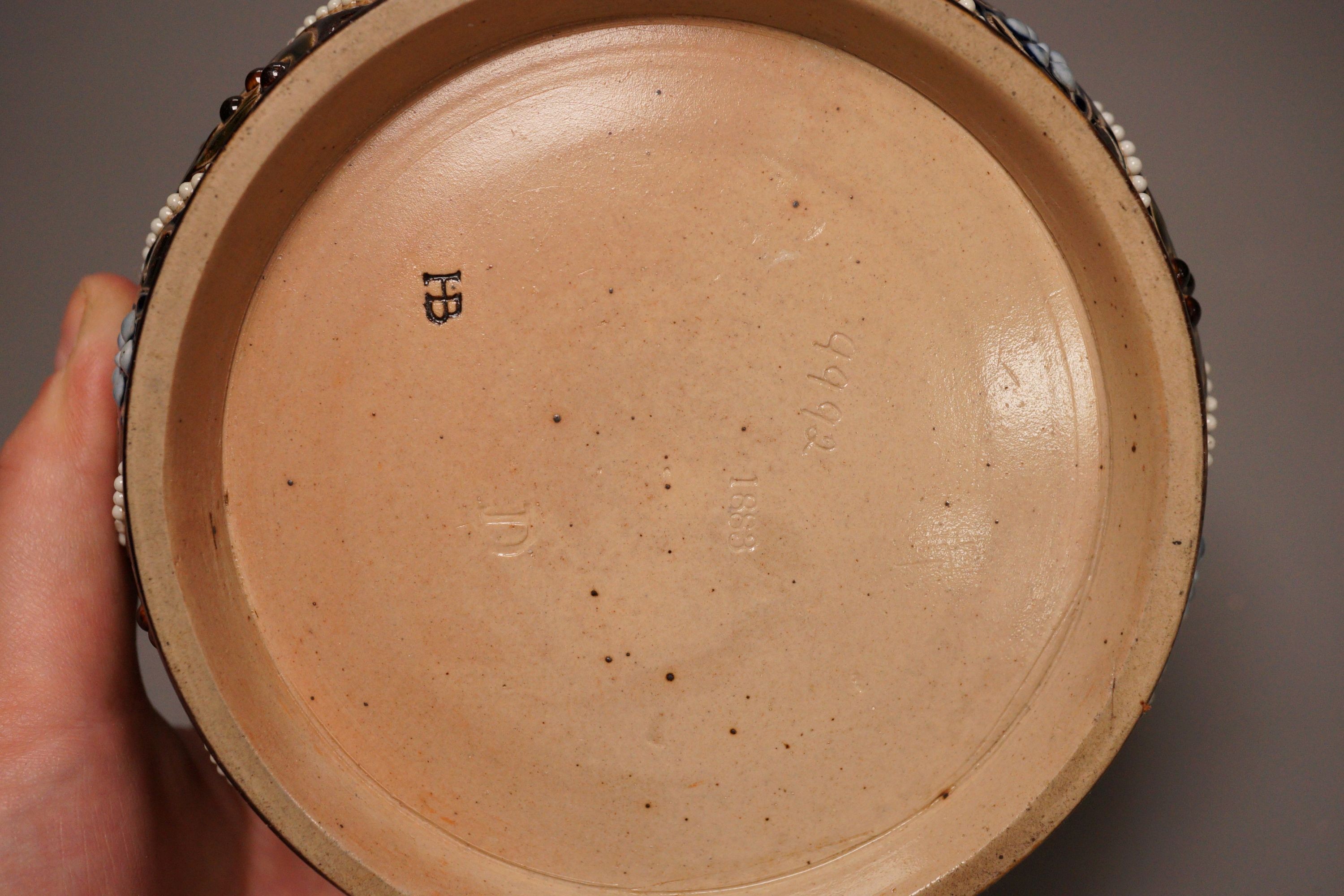 A Doulton style salt glaze stoneware lidded jar, marked HB, 8cm tall